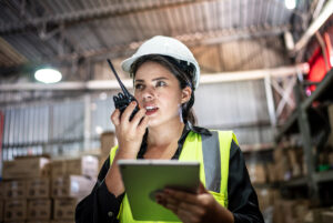 Young woman talking on the walkie-talkie in a warehouse